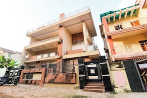Un edificio de varios pisos con balcones, una entrada con puerta y un letrero que indica zona sin estacionamiento.