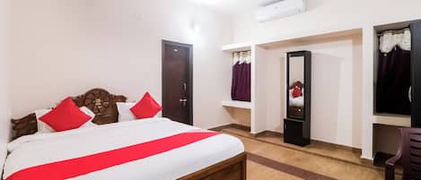 Habitación de hotel con una cama, ventilador de techo, puerta y espejo.