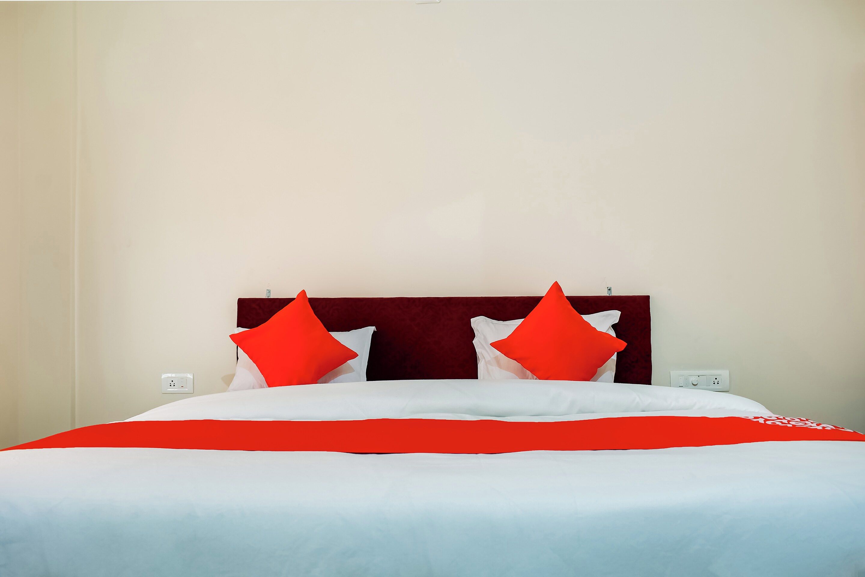 A bed with a red and white bedspread, two red pillows, and a dark headboard.