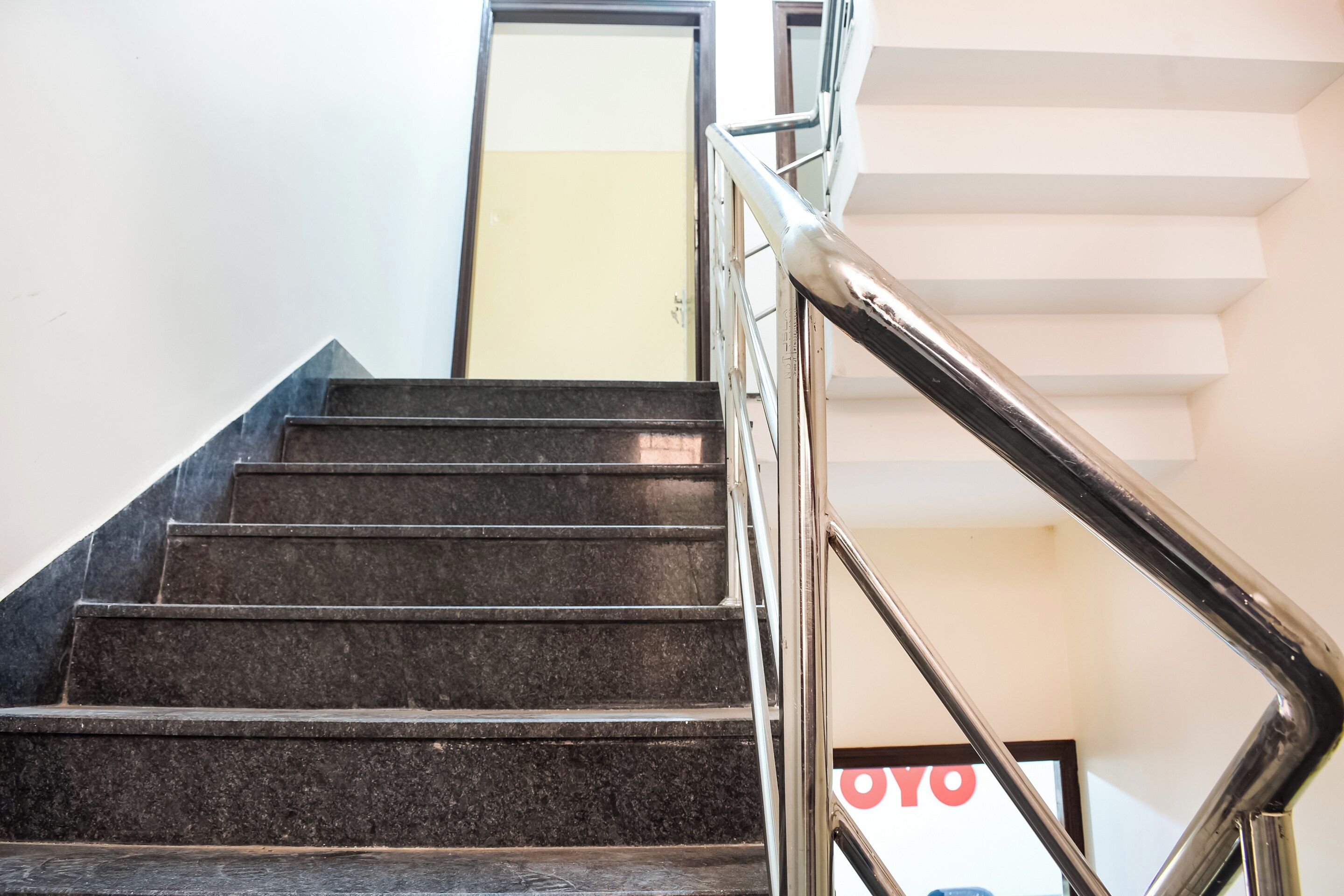 Una escalera con barandilla de metal que conduce a una puerta con un letrero que dice 'OYO'.