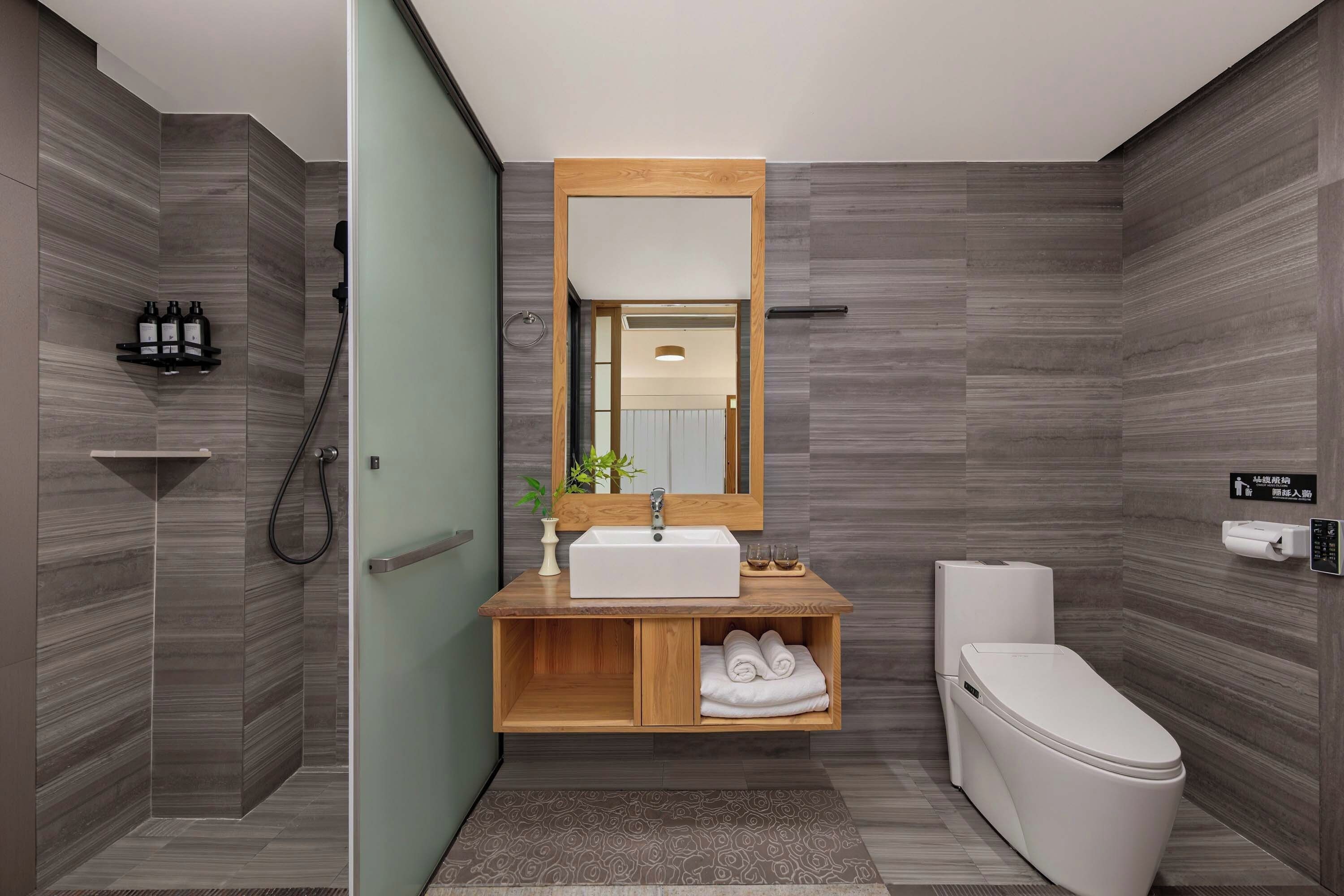 Une salle de bain moderne avec un meuble-lavabo en bois, des toilettes et un espace douche.