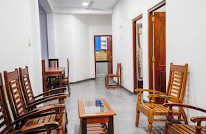 Un pasillo con sillas de madera y una pequeña mesa, que conduce a una habitación con cama y armario.
