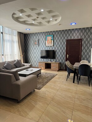 Een moderne woonkamer met een bank, salontafel, televisie en eethoek.