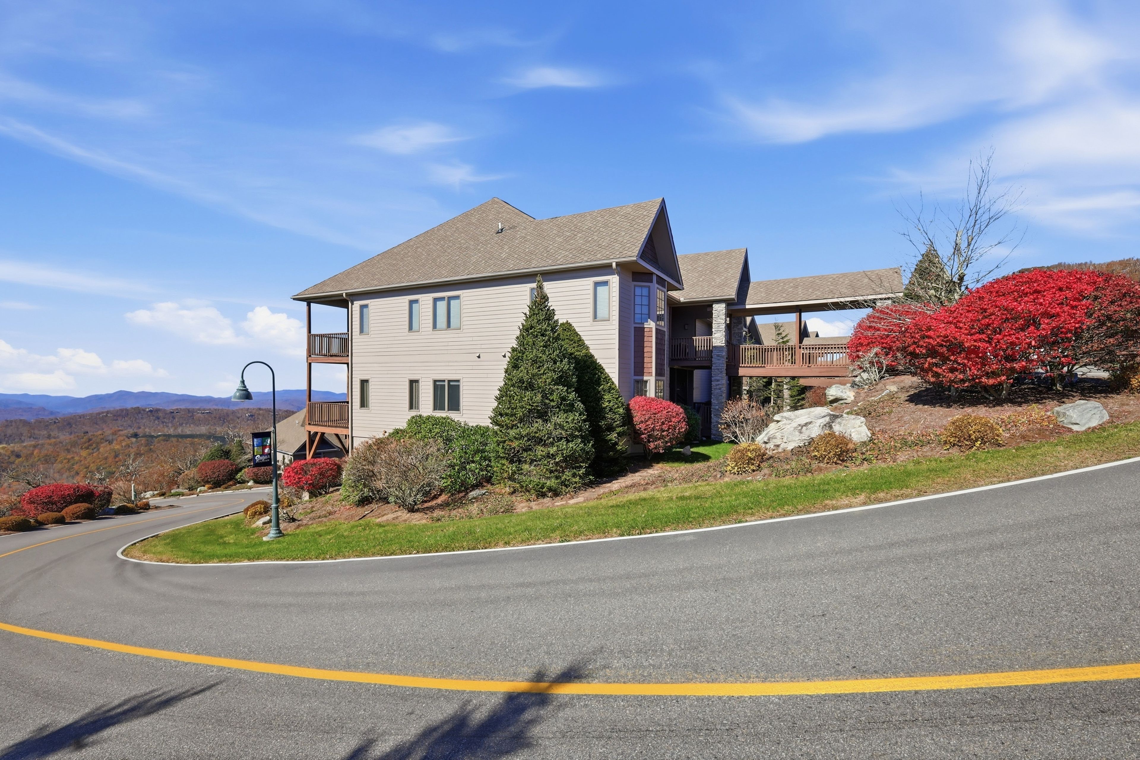 A two-story house with a balcony, a driveway, and a street lamp.