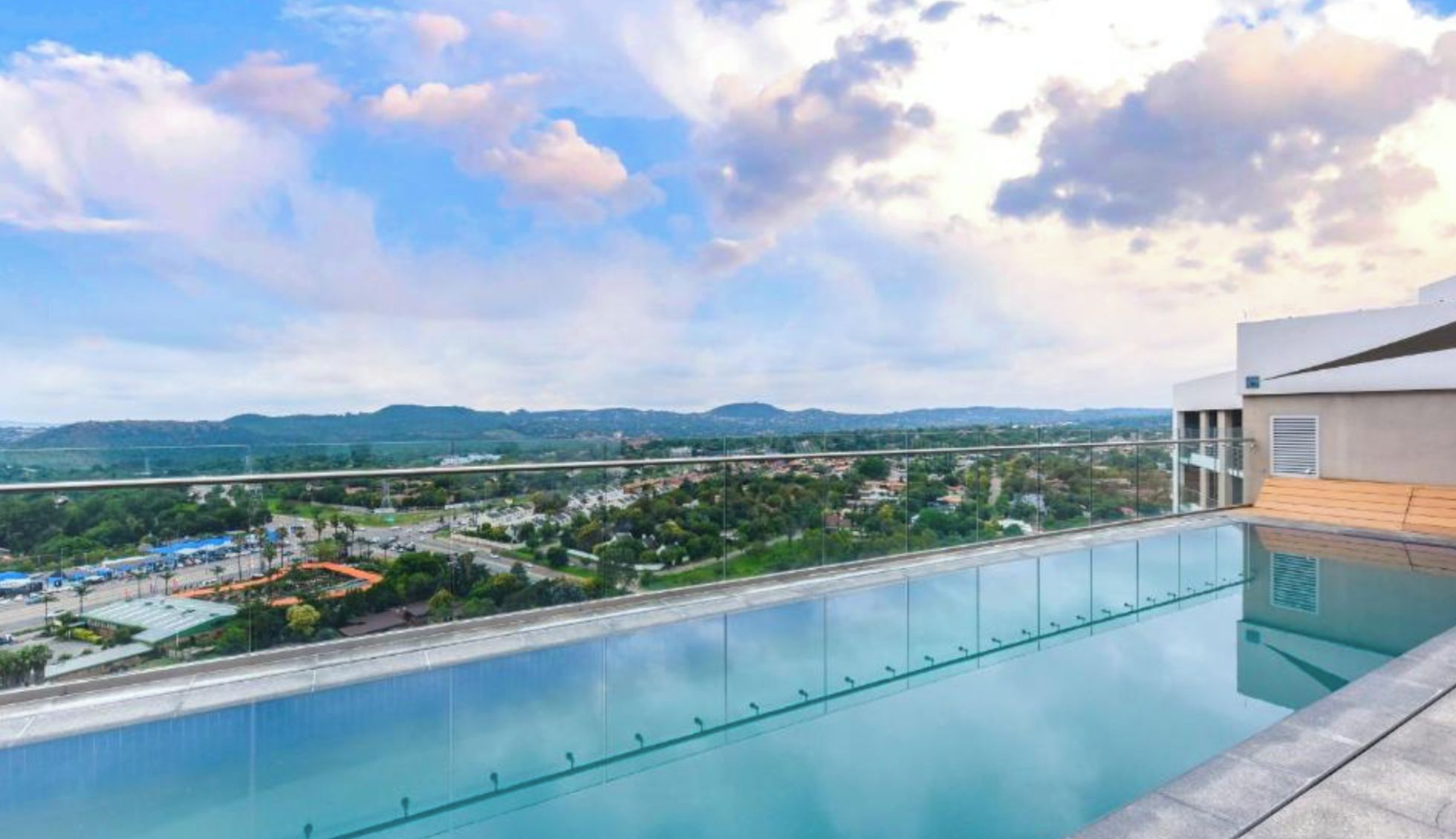A rooftop pool with a clear view of a cityscape and distant mountains.