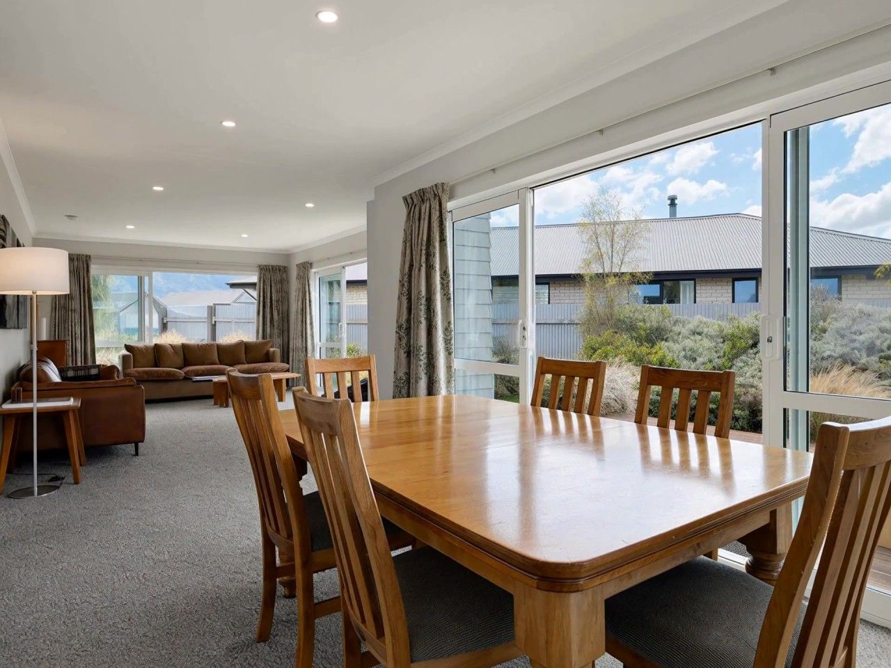 Une pièce spacieuse avec une grande table à manger en bois, des sièges confortables et de grandes fenêtres offrant une vue sur le paysage environnant.