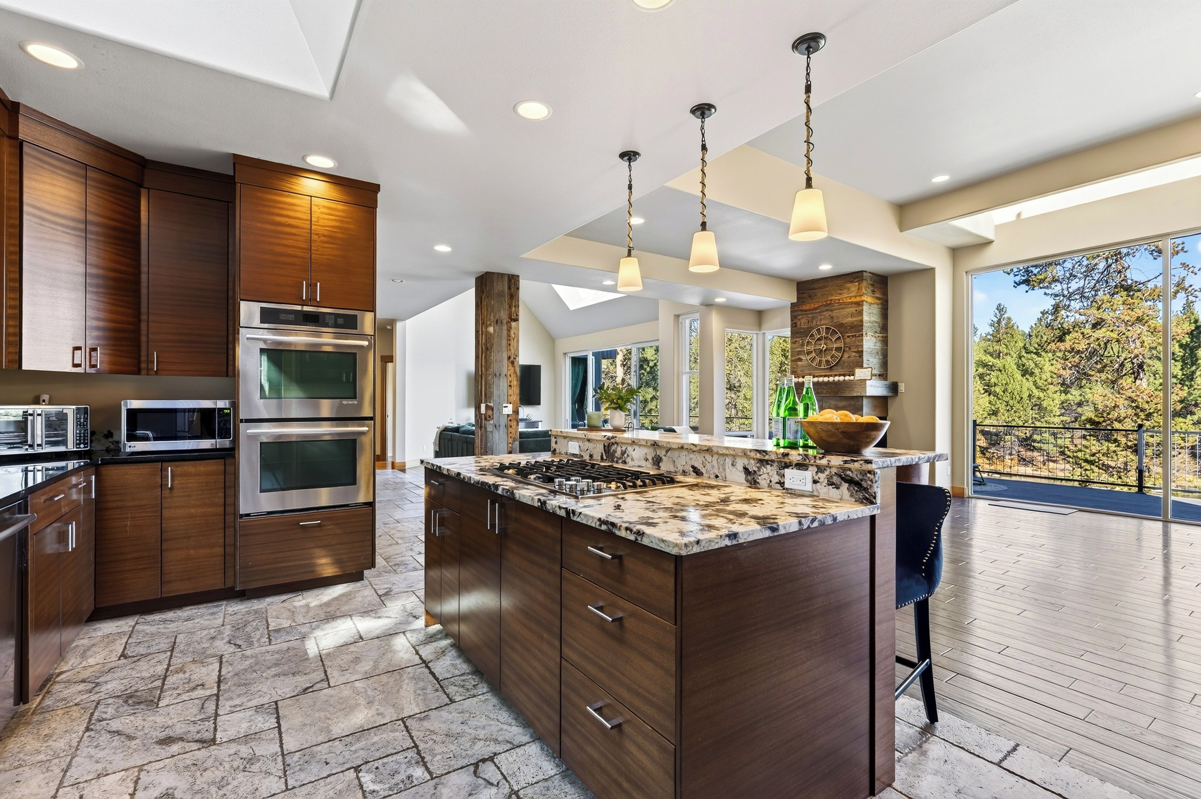 A modern kitchen with built-in appliances, a large island, and a view to the outdoors.