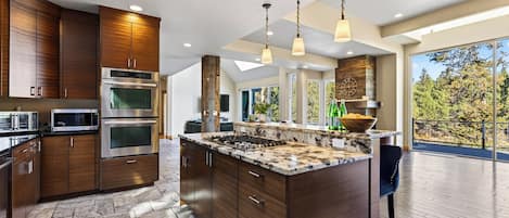 A modern kitchen with built-in appliances, a large island, and a view to the outdoors.