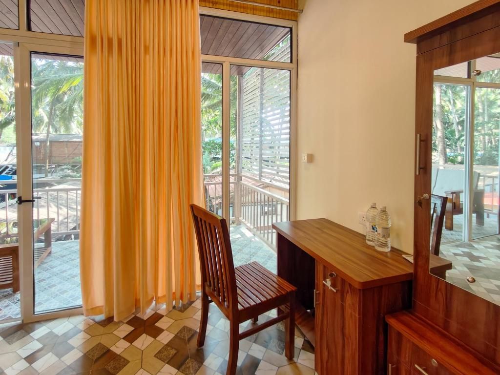 A room with a wooden desk, a chair, and a large window with curtains.