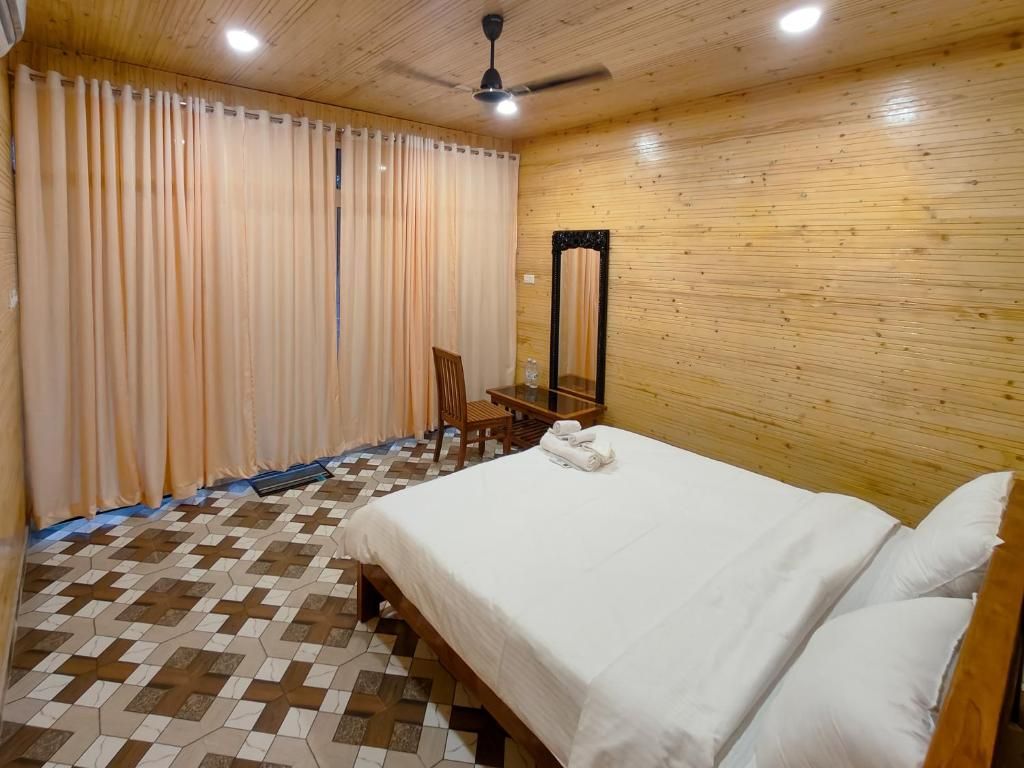 A bedroom with a bed, a chair, a mirror, and a ceiling fan.