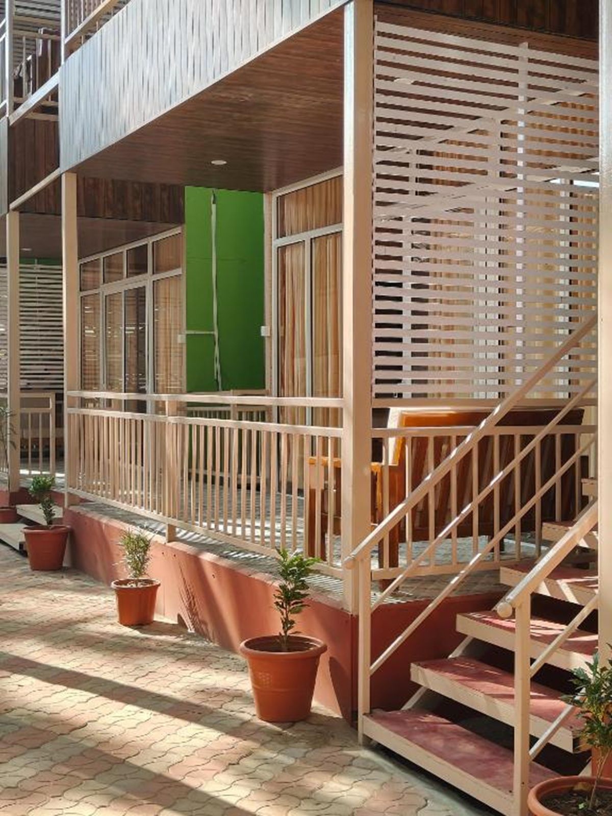 A building with a wooden staircase, a green door, and potted plants.