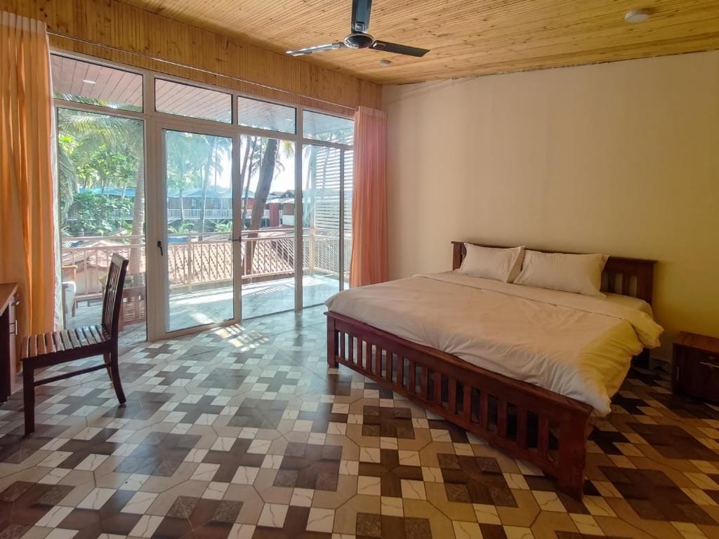 A bedroom with a bed, a chair, and a view of a balcony.