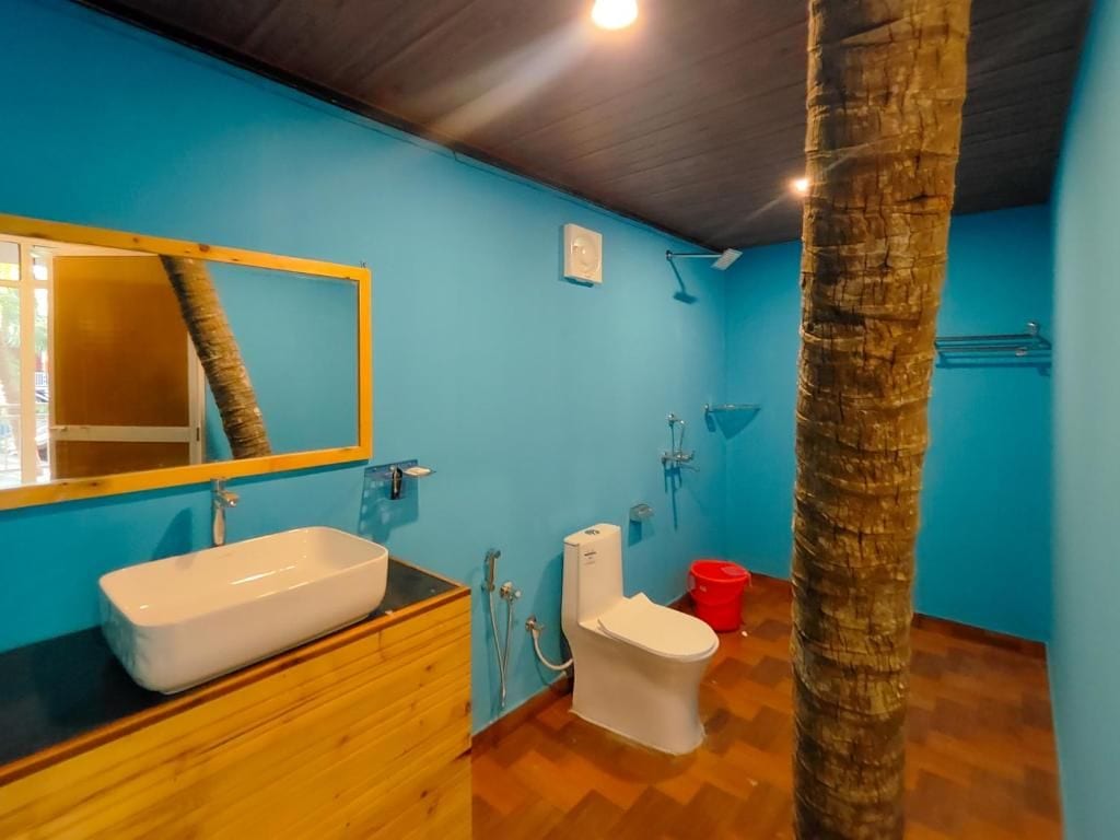 Un baño con tocador de madera, lavamanos blanco, inodoro y zona de ducha.