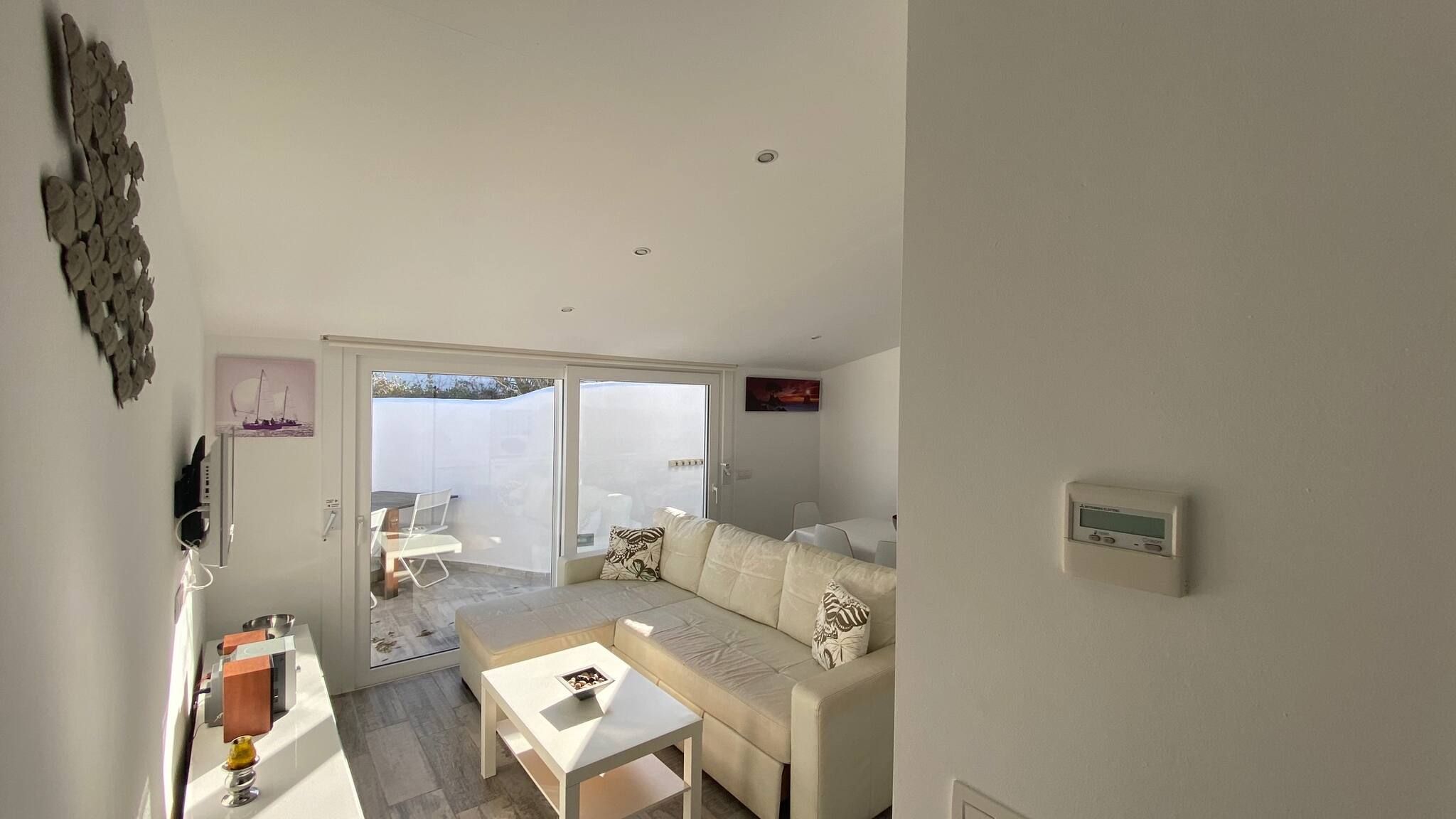 Un salon moderne avec un canapé, une table basse et une porte-fenêtre coulissante donnant sur une terrasse.