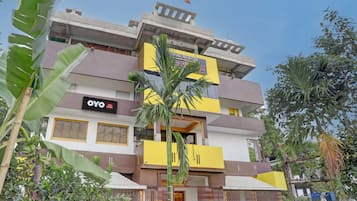 Un hotel de varios pisos con balcones, un cartel que dice 'OYO Hotel Midnight' y follaje circundante.
