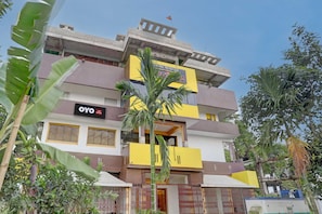 Un hotel de varios pisos con balcones, un cartel que dice 'OYO Hotel Midnight' y follaje circundante.