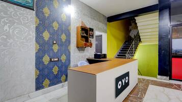 Una recepción con un letrero, una escalera y paredes con diseño.