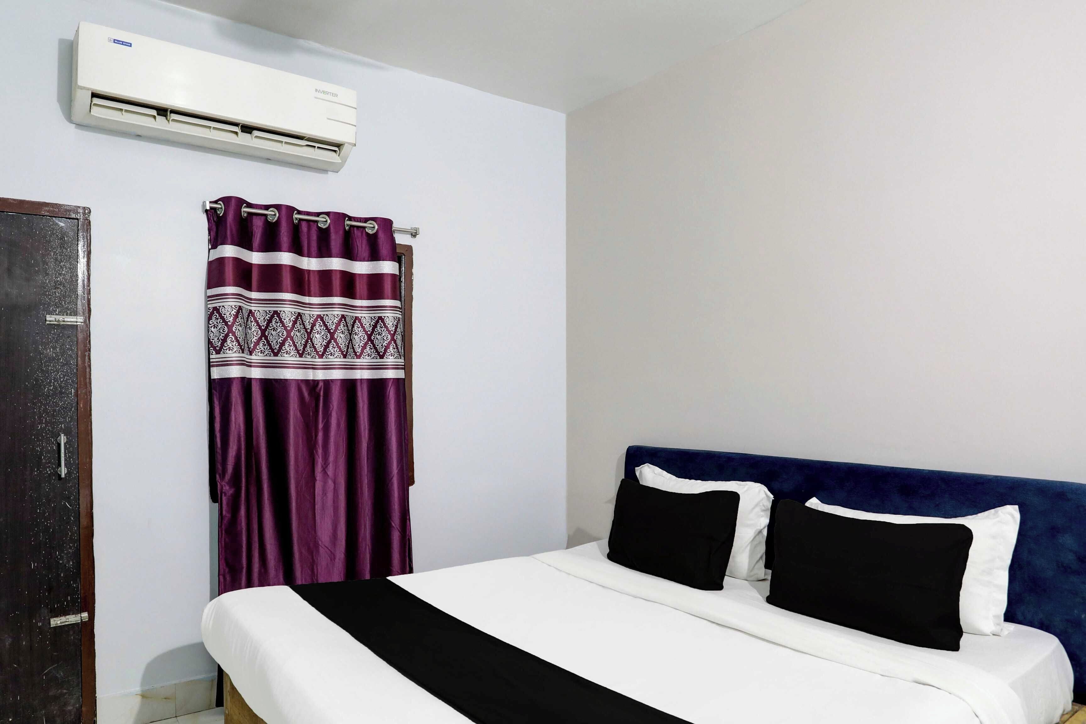 Una habitación de hotel con una cama, una cortina y un equipo de aire acondicionado.