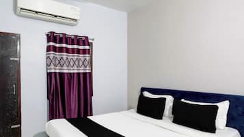 Una habitación de hotel con una cama, una cortina y un equipo de aire acondicionado.