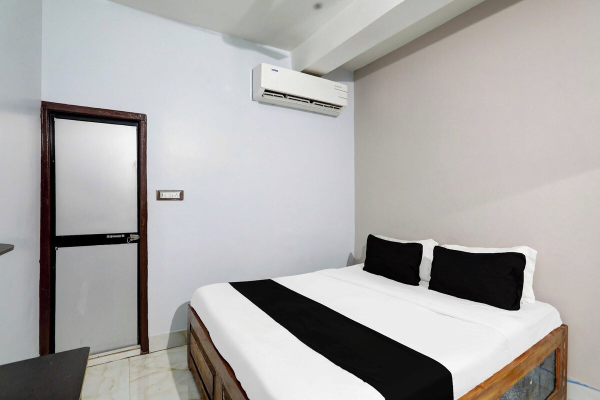 Un dormitorio con cama, una puerta, un equipo de aire acondicionado y una mesita.