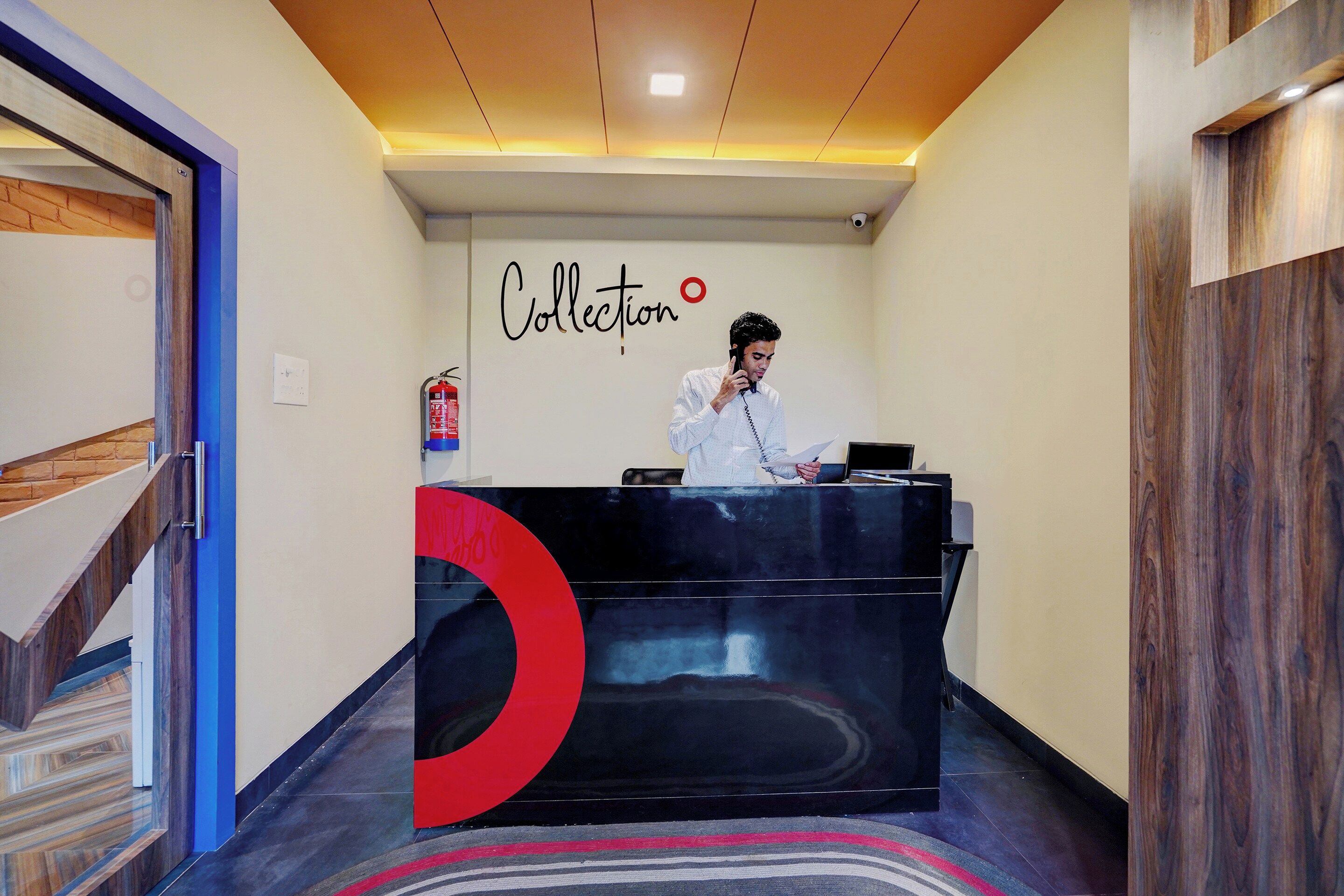 Una recepción con logotipo, un extintor y un sistema de intercomunicación instalado en la pared.
