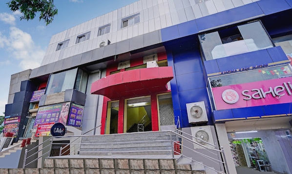 A multi-story building with a prominent red and blue facade, a visible staircase, and a storefront with a pink sign. - Super Collection O Kalinga Bapuji Nagar (Bhubaneswar)