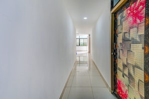 Un pasillo con paredes blancas, piso de baldosas y una puerta con estampado floral.