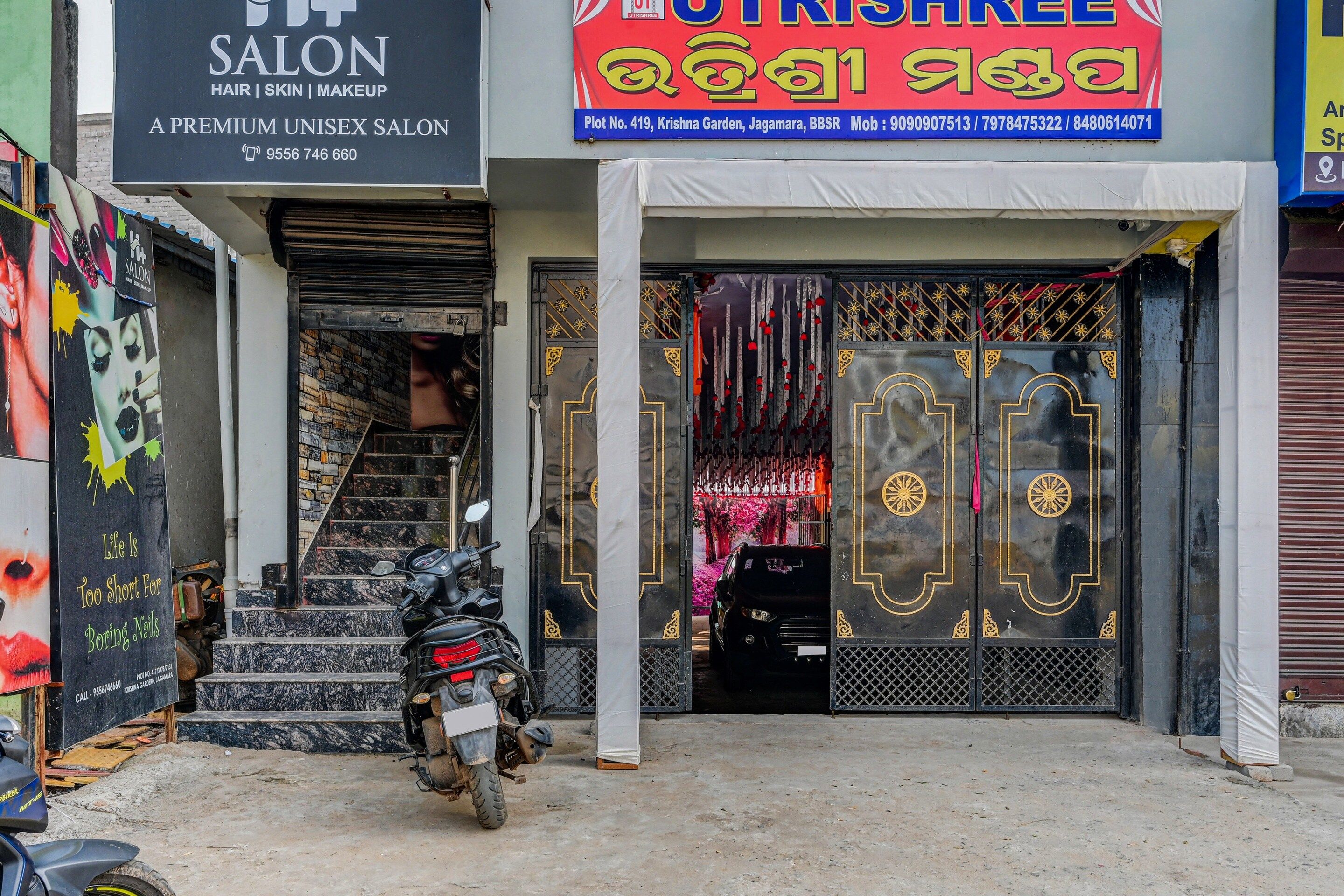 A salon with a closed shutter and a motorcycle parked in front.
