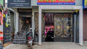 A salon with a closed shutter and a motorcycle parked in front.