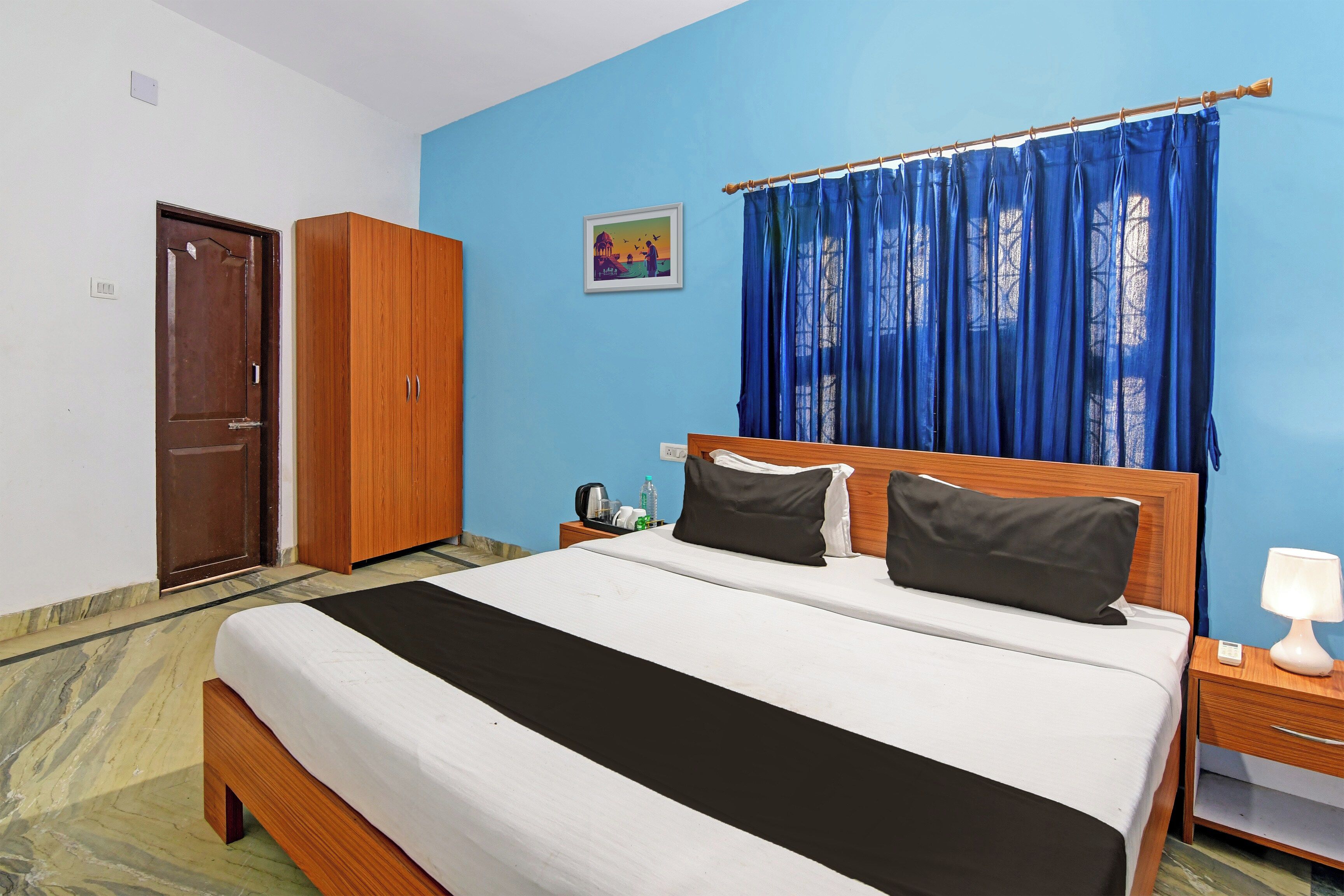 A hotel room with a bed, a wardrobe, a nightstand, and a window with curtains.