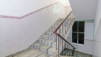 Eine Treppe mit Marmorstufen und einem Metallgeländer, die zu einer Zwischenebene mit einem Fenster führt.