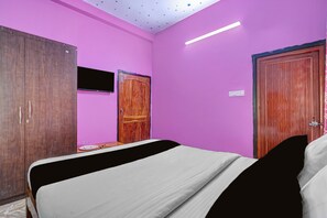 A bedroom with a bed, a wardrobe, a television, and a door. - Hotel O Dream 11 (Bhubaneswar)