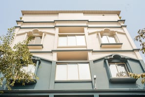 Um edifício de vários andares com fachada simétrica, janelas amplas e uma varanda central.