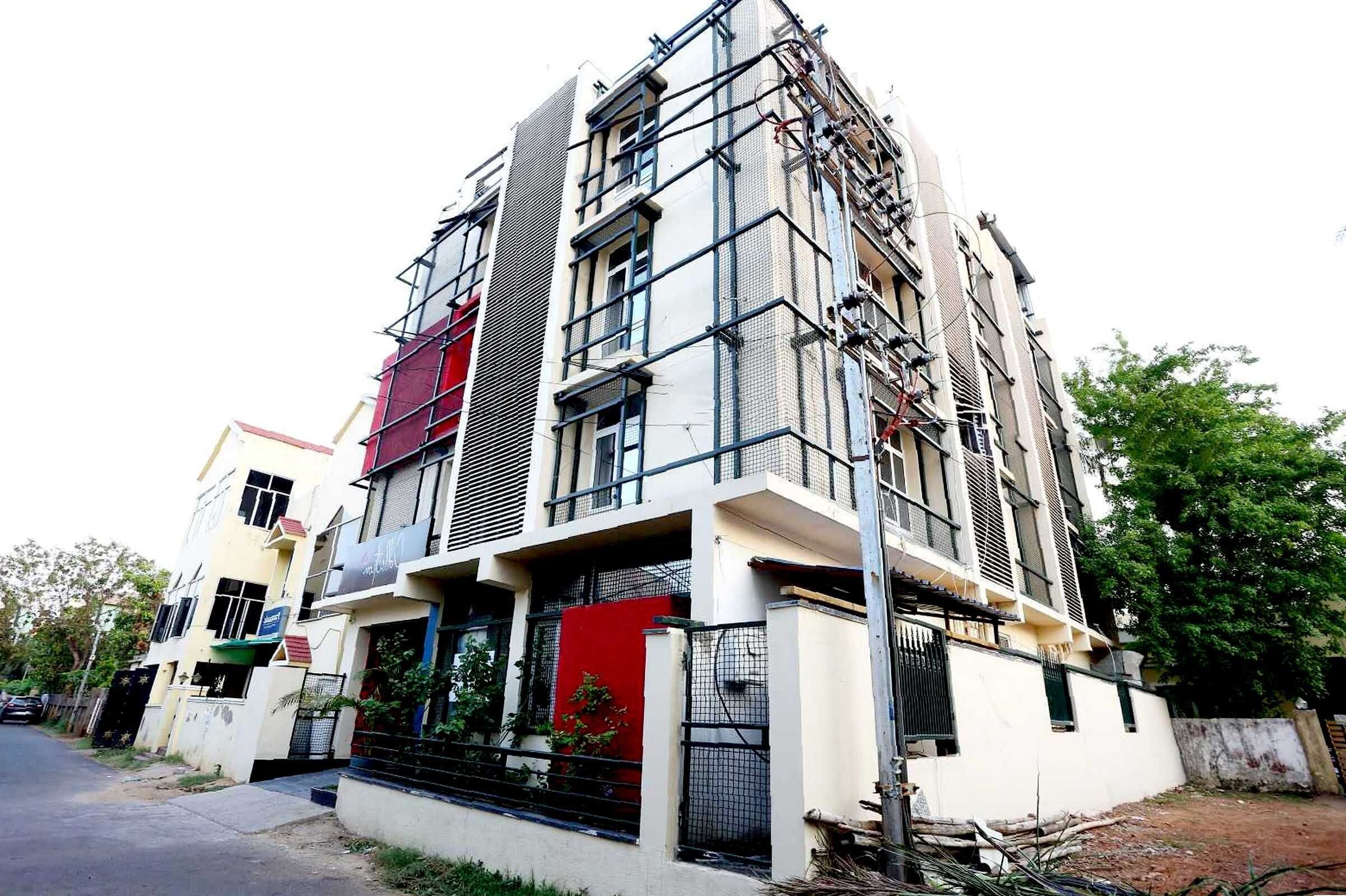 Un edificio residencial de varios pisos con un balcón y una puerta roja.