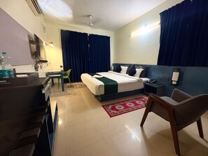 A hotel room with a bed, desk, chair, and a small table with a lamp. - Super Collection O Vastukar Retreat (Bhubaneswar)