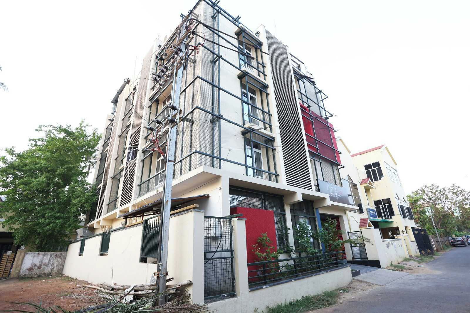 A multi-story residential building with a balcony, a gated entrance, and a visible utility pole.