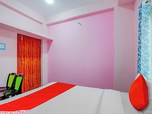 Quarto com cama, guarda-roupa e escrivaninha com duas cadeiras.