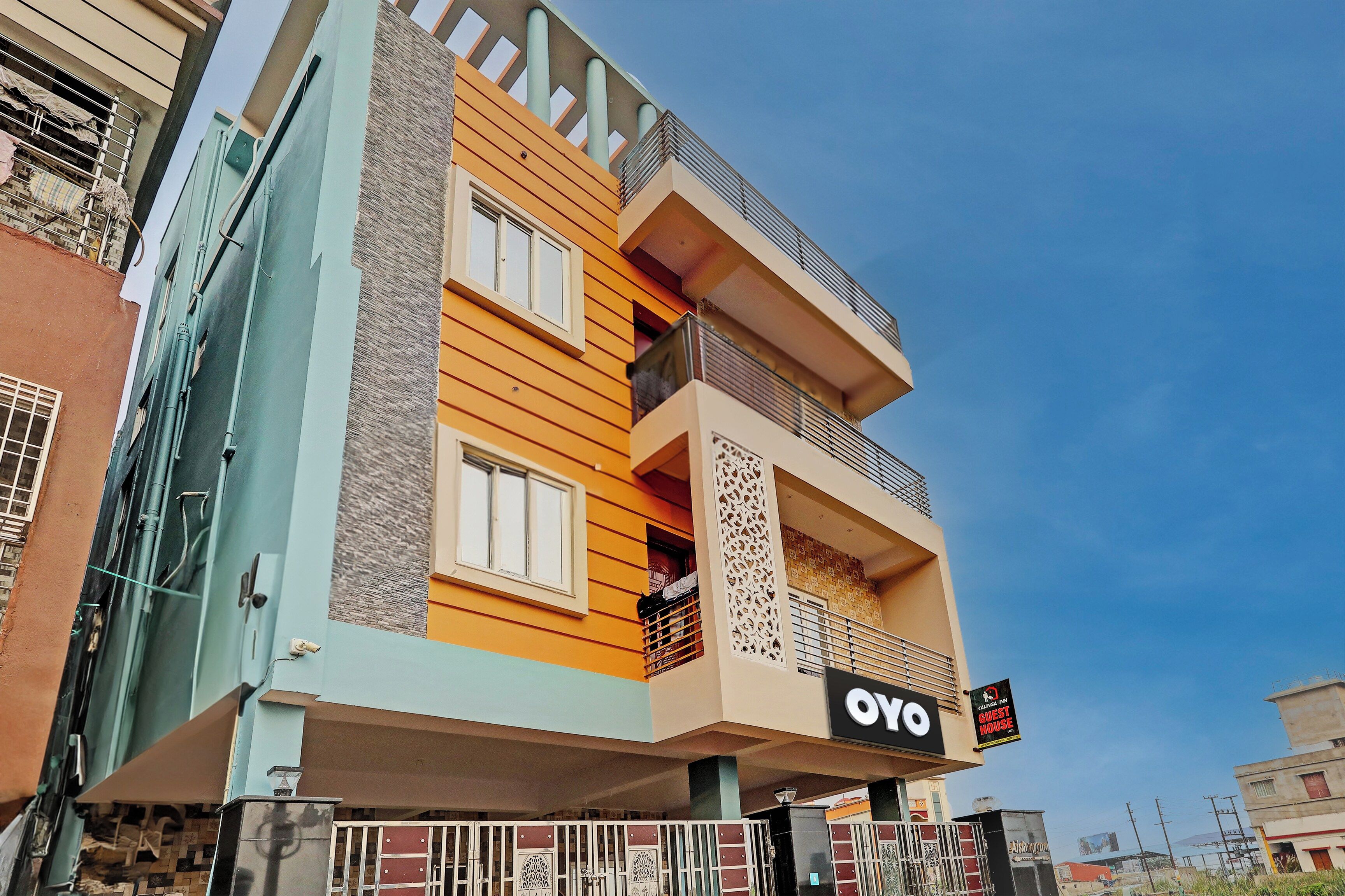 A multi-story building with balconies, a sign for 'Kalinga Inn Guest House,' and a clear sky.