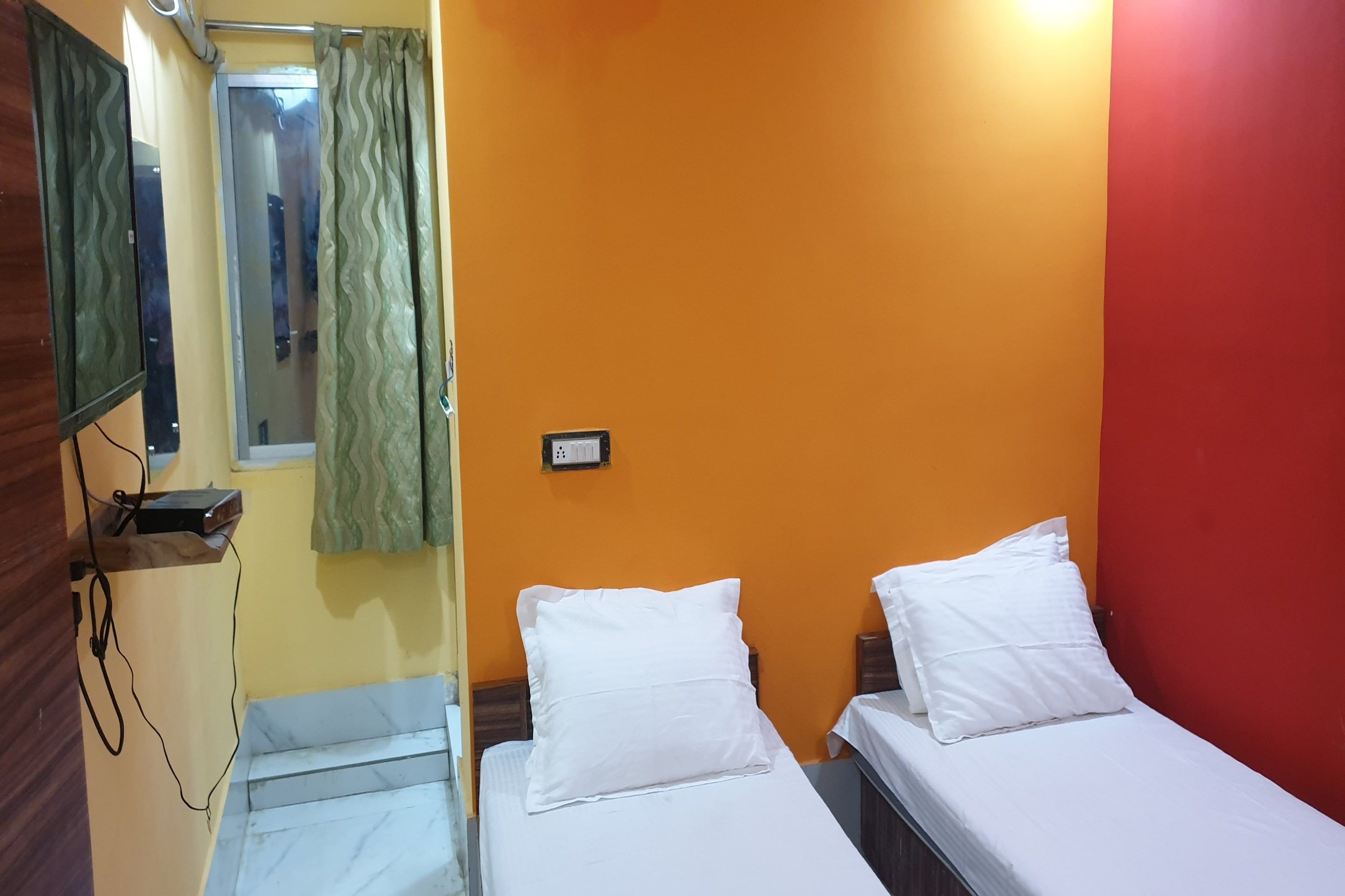 A room with two beds, a mirror, and a window with curtains.