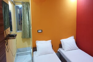 Una habitación con dos camas, un espejo y una ventana con cortinas.