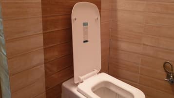 Un inodoro blanco con el asiento cerrado y un tirador de la cadena en la pared.