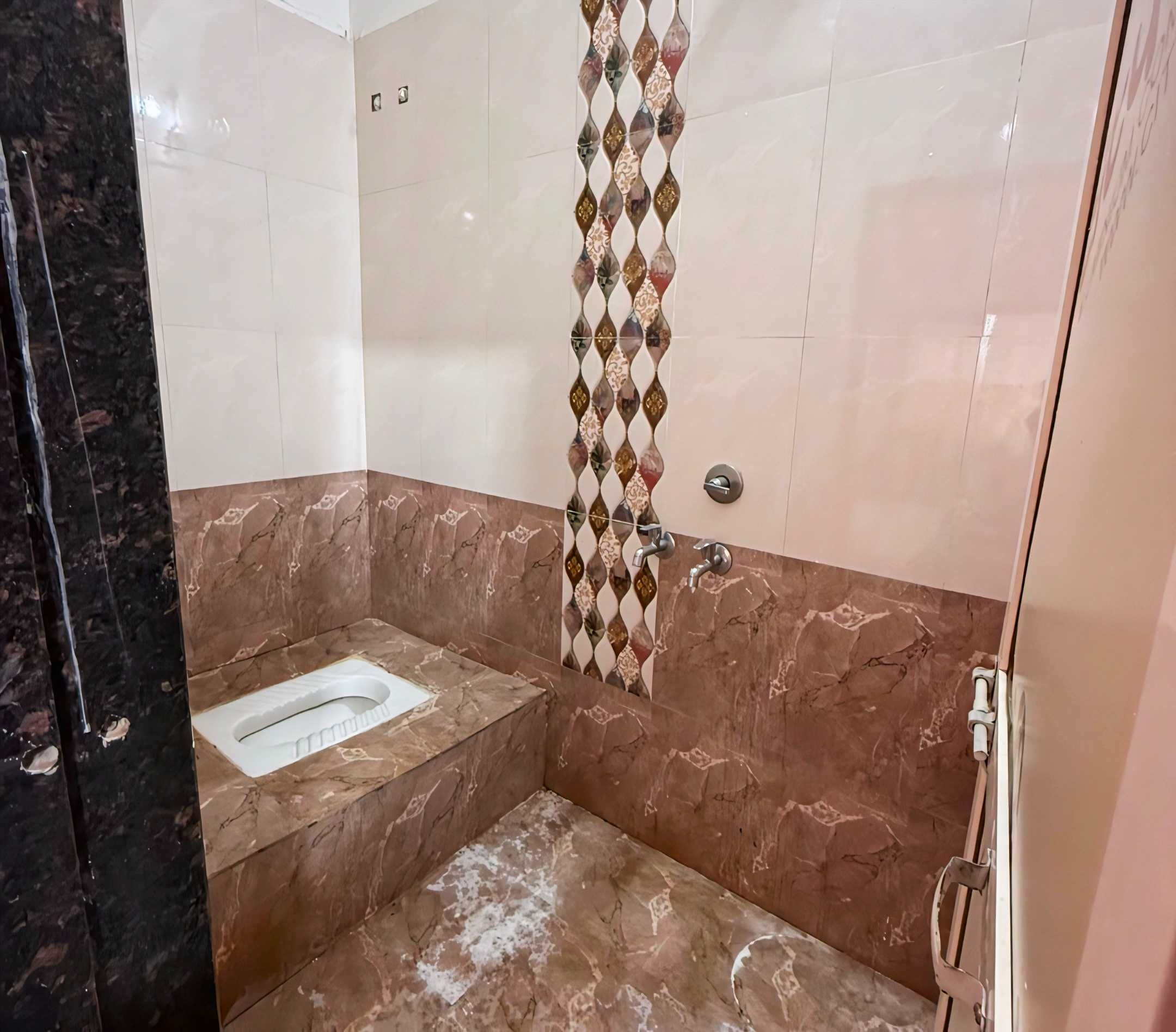 A bathroom with a toilet, a shower area, and a marble floor.