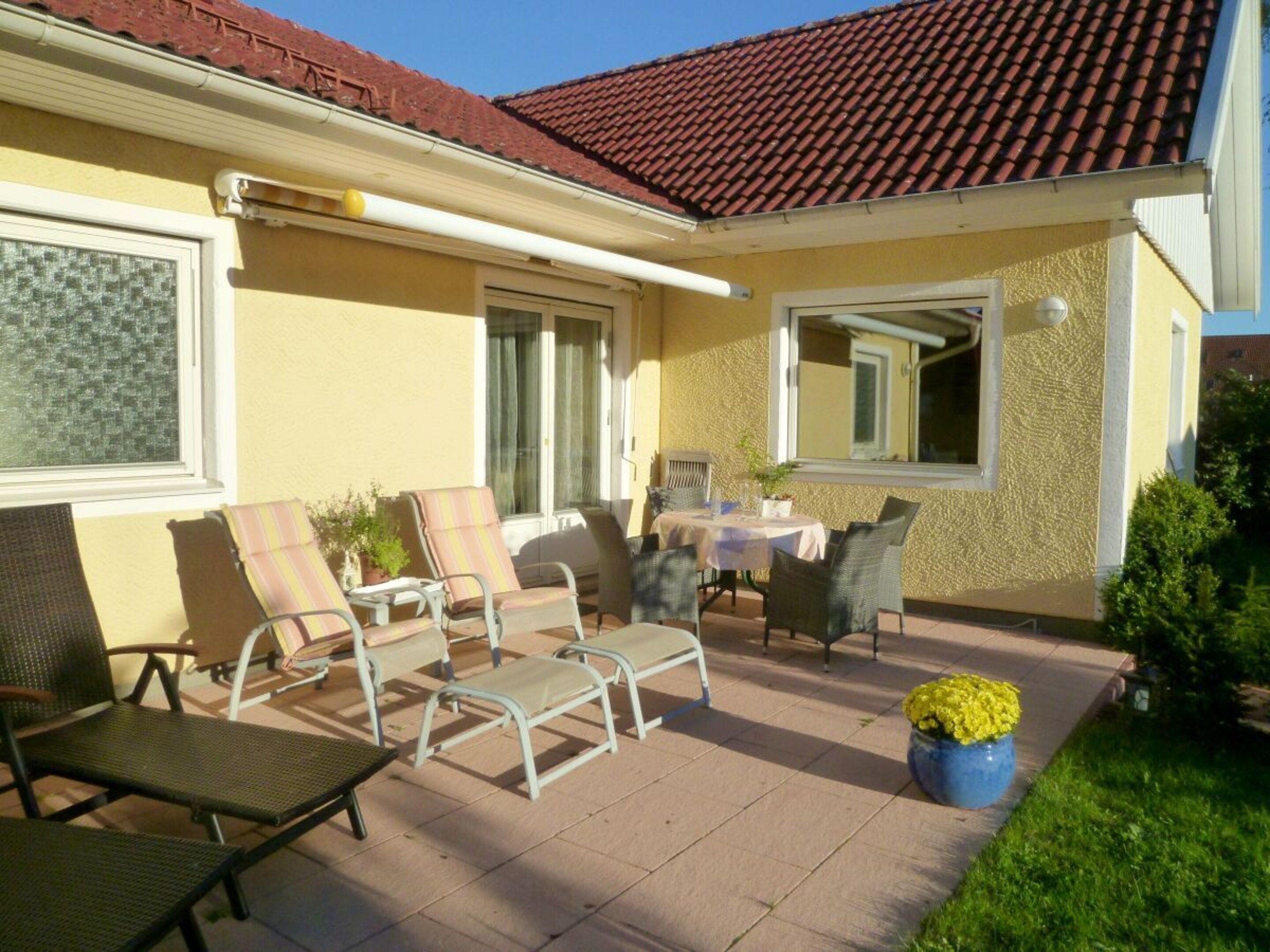 A patio with outdoor furniture, a table, and a potted plant.