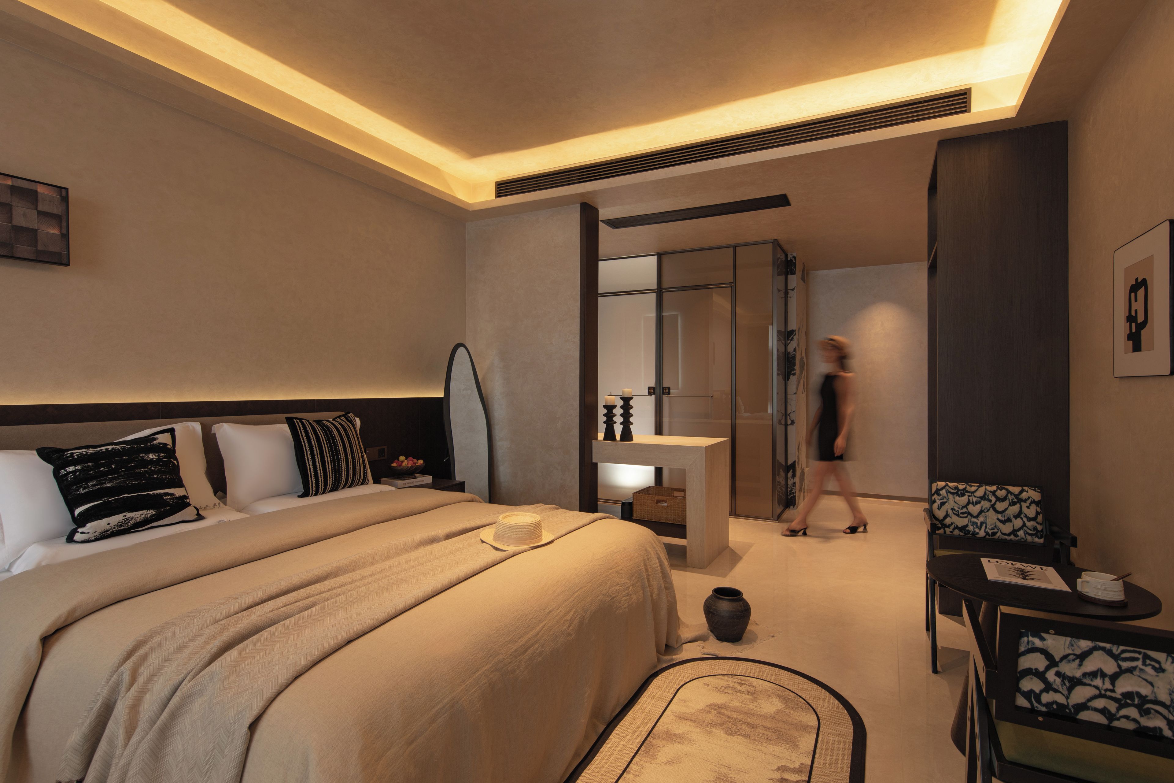 A hotel room with a bed, bedside table, and a desk with a chair.