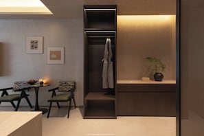 A compact room with a built-in closet, a small table with chairs, and a potted plant. - Carefree Garden Hotel (Lijiang)