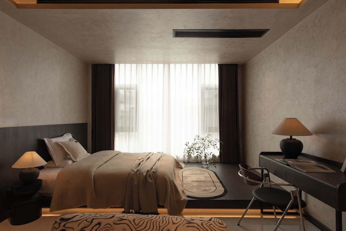 Een moderne hotelkamer met een bed, bedlampjes, een bureau en een stoel.