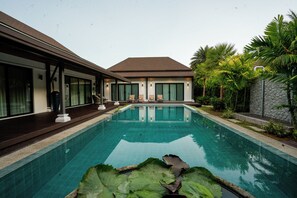 Ein Swimmingpool mit freiem Blick auf die Umgebung, darunter ein Gebäude mit großen Fenstern und einer überdachten Terrasse.
