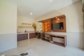 A modern kitchen with a built-in TV, wooden cabinets, and a dining area. - Aluh Lovina Villa (Buleleng)