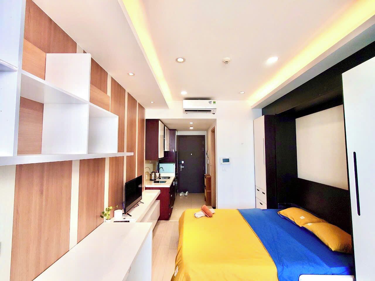 A hotel room with a bed, a desk, a television, and a kitchenette.