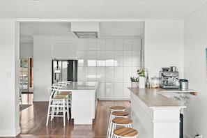 Una cocina moderna con una isla central, taburetes de bar y una máquina de café.